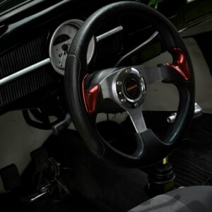 Close-up view of a vintage car's steering wheel, showcasing classic design and style.