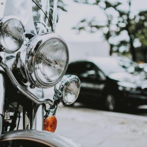 Detailed view of motorcycle headlights with blurred car on street.